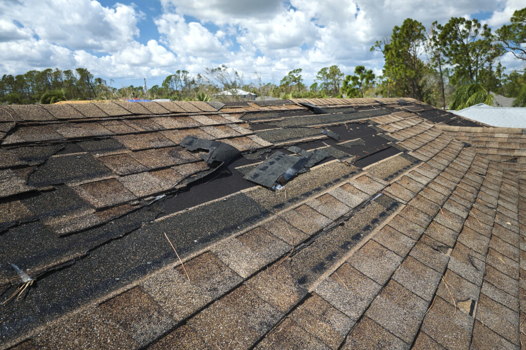 Storm Damage Roof Insurance Claim Damaged house roof with missing shingles after a storm.