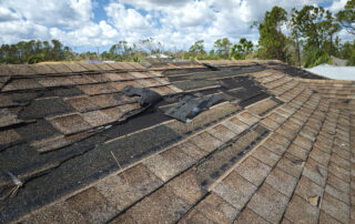 Damaged house roof with missing shingles after a storm.